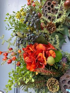 a close up of a wreath with flowers and pine cones