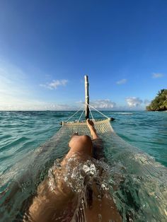 a person laying on a hammock in the ocean with their feet up and head down