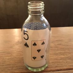 a glass jar filled with playing cards on top of a wooden table