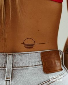 the back of a woman's stomach with a small sun tattoo on her left side