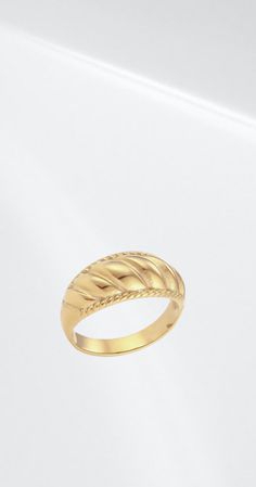 a yellow gold ring with braiding on the side, sitting on a white surface