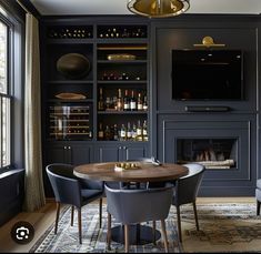 a dining room table with chairs around it in front of a fire place and built - in bookshelves