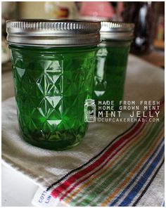 two green mason jars sitting on top of a white table cloth next to each other