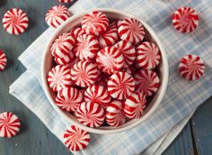 a bowl filled with red and white candy canes on top of a blue cloth