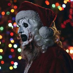 a man dressed as santa claus in front of a christmas tree with lights behind him