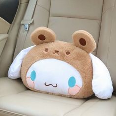 a teddy bear pillow sitting in the back seat of a car with it's eyes closed