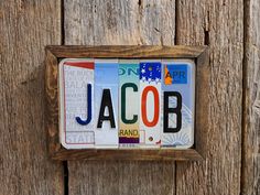 a close up of a license plate on a wooden fence with the word jacob painted on it