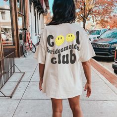 a woman is walking down the sidewalk wearing a t - shirt that says go bridesmaids club