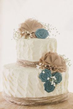 a three tiered cake with blue and brown flowers on it's side, sitting on a table