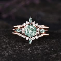 a green and white diamond ring on top of a black stone surface with diamonds around it