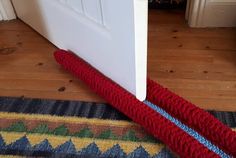 a red roped up umbrella laying on the floor next to a door and rug