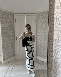 a woman is taking a selfie in the mirror with her cell phone while wearing a black and white dress