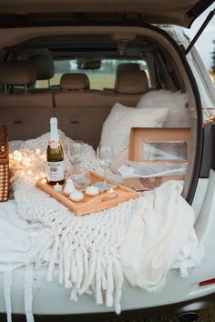 the trunk of a car filled with blankets and bottles of wine on top of it