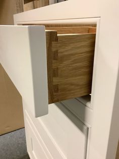 a close up view of an open drawer in a kitchen cabinet that is white and wood