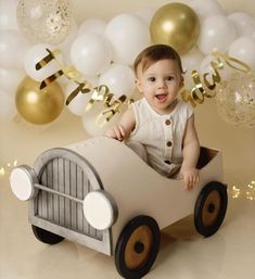 a baby sitting in a toy car surrounded by balloons