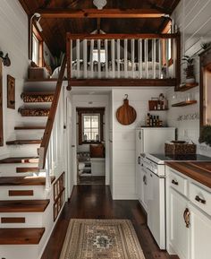 a kitchen with white cabinets and wooden floors next to a staircase leading up to the second floor