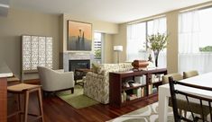 a living room filled with furniture and a fire place in front of a window on top of a hard wood floor