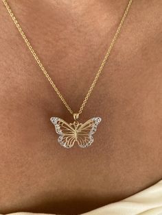 a woman wearing a gold necklace with a butterfly pendant on it's back neck