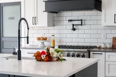 a kitchen with white cabinets and an island in front of the stove top is decorated with flowers