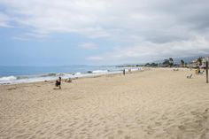 people are walking on the beach near the ocean