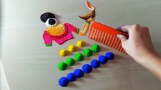 a child's hand is holding a comb and scissors next to colorful felt toys