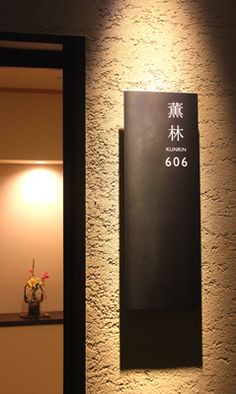 a sign on the side of a building that says 606 in chinese and has a vase with flowers next to it