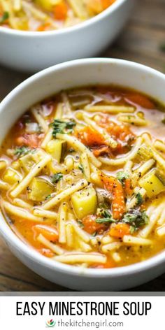 two white bowls filled with vegetable soup on top of a wooden table