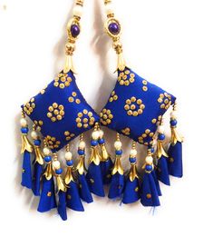 a pair of blue and gold earrings with tassels hanging from the side on a white surface