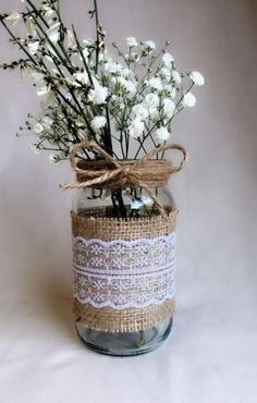 a mason jar filled with white flowers and twine