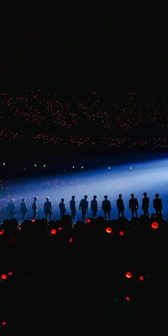 a group of people standing in the dark with pumpkins lit up at night time