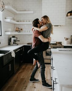 a man holding a woman in his arms while standing on top of a kitchen counter