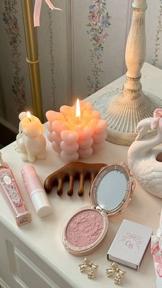 a table topped with makeup and candles next to a candle holder on top of a dresser