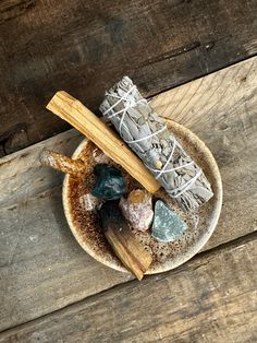 a bowl filled with different types of rocks on top of a wooden table next to a rolling pin