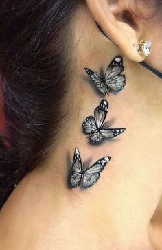 the back of a woman's neck has three butterflies on it and one behind her ear