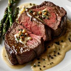 two steaks with sauce and asparagus on a plate