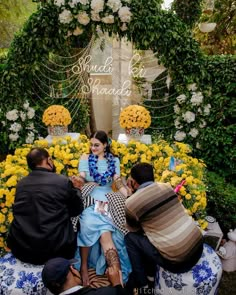 three people sitting on top of a blue and white flower covered bench with yellow flowers in the background