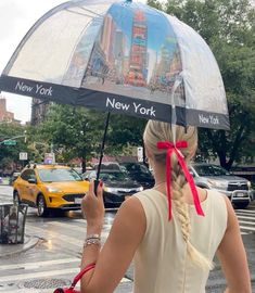 a woman holding an umbrella in the rain on a city street with new york and new york