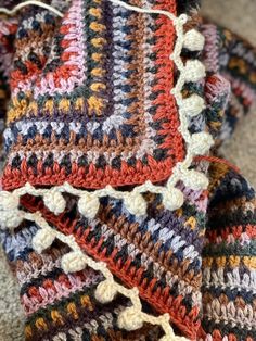 multicolored crocheted blanket laying on the floor