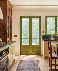 a green door in a kitchen next to a stove top oven and dining room table