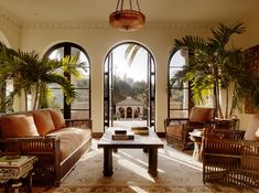 a living room filled with lots of furniture and large arched windows next to each other