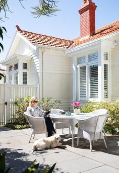 a woman sitting at a table with a dog on the ground in front of her