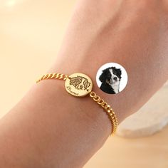 a woman's arm with a gold bracelet and a dog photo on it