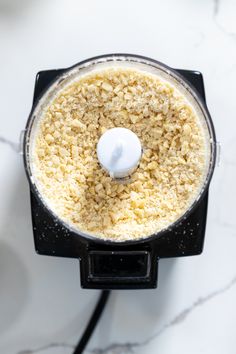 an overhead view of a food processor on a marble counter top with white stuff in it