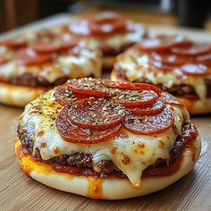 three mini pizzas with pepperoni and cheese on them sitting on a cutting board