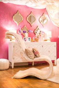 a white swan shaped chair sitting on top of a hard wood floor next to a pink wall