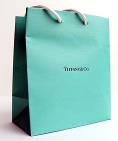 a tiffany & co bag sitting on top of a white table with the words tiffany and co written on it