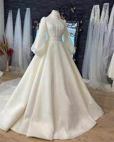 a white wedding dress on display in front of mannequins