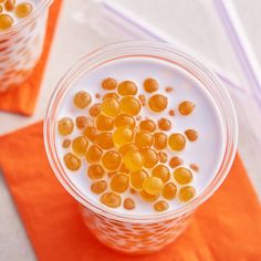 two cups filled with milk and jelly on top of a yellow table cloth next to chopsticks