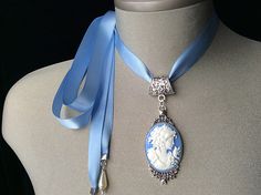 Blue Cameo Choker! This beautiful "Wedgwood Blue" cameo has been set in an antique silver pendant and attached to a blue satin ribbon.... I have added teardrop pearls to the end of each tie... The perfect Mother's Day gift for all those amazing and devoted Mom's! Ribbon is available in light Wedgwood blue, black or pearl greyplease choose from the menu Please select if you would like this item gift wrappedI will also include a card with your personal message.... Thank you for taking time to browse my shop Veronica Rose Designs.... https://www.etsy.com/shop/veronicarosedesigns?ref=seller-platform-mcnav Blue Cameo Jewelry For Wedding, Blue Cameo Necklace For Wedding, Blue Medallion Necklaces For Wedding, Blue Medallion Necklace For Wedding, Cameo Pendant Necklace For Wedding, Blue Cameo Necklace For Formal Occasions, Victorian Blue Cameo Jewelry, Cameo Choker, Victorian Cameo