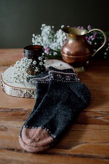 two pairs of socks sitting on top of a wooden table next to a potted plant